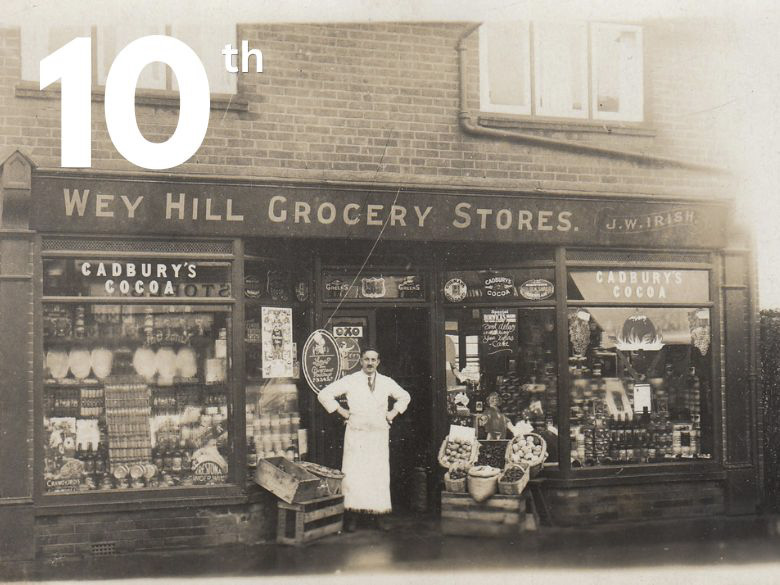 An Edwardian shopkeeper in front of his grocery shop